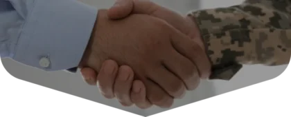 A person in a blue dress shirt shaking hands with a person in a military camouflage uniform